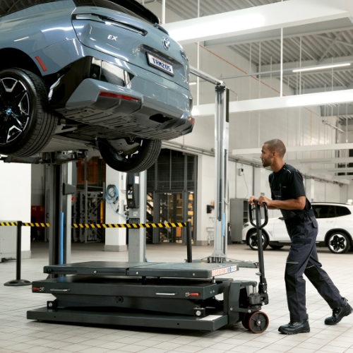 BMW Trained Technician replaces BEV car battery on a BMW vehicle on a lift in a BMW Certified Collision Repair Center.